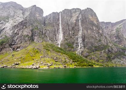 Rocky coastline of Lysefjord with cliffs, waterfalls and green water lagoon, Forsand municipality, Rogaland county, Norway