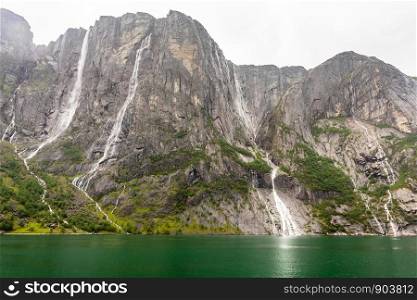 Rocky coastline of Lysefjord with cliffs, waterfalls and green water lagoon, Forsand municipality, Rogaland county, Norway