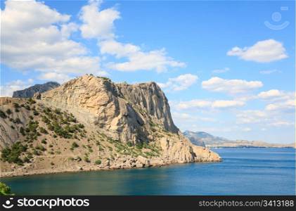 "rocky coastline with pine trees on blue sky and sea background ("Novyj Svit" reserve, Crimea, Ukraine)."