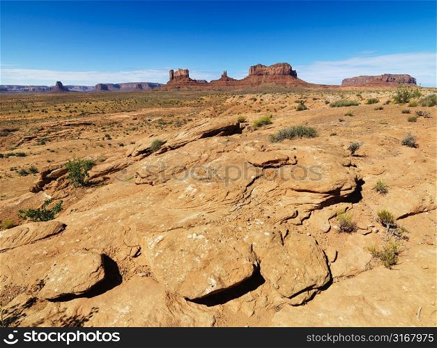 Rocky desert landscape with landforms and mountains.