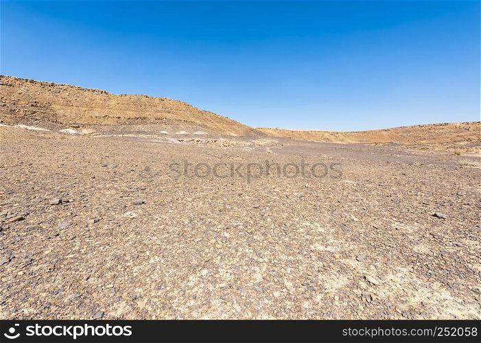 Rocky hills of the Negev Desert in Israel. Breathtaking landscape of the rock formations in the Southern Israel. Dusty mountains interrupted by wadis and deep craters.