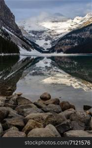 Rocky mountain reflection on Lake Louise with rock shore in Banff National Park, Alberta, Canada