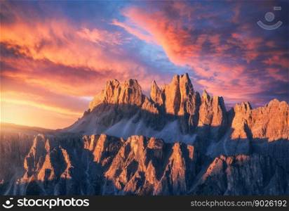 Rocky mountains at amazing colorful sunset in summer in Dolomites, Italy. Mountain ridges and beautiful sky with pink, red and ornage clouds and sunlight in spring. Landscape with rocks, mountain peak