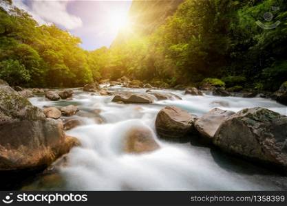 Rocky river landscape in rainforest with mountains background. Shot at Tutoko River near Milford Sound in Fiorland National Park, South Island of New Zealand.
