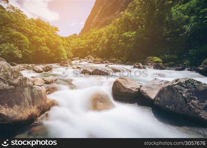 Rocky river landscape in rainforest with mountains background. Shot at Tutoko River near Milford Sound in Fiorland National Park, South Island of New Zealand.
