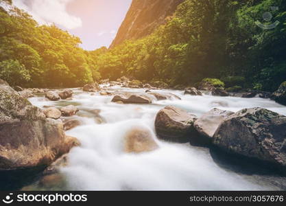 Rocky river landscape in rainforest with mountains background. Shot at Tutoko River near Milford Sound in Fiorland National Park, South Island of New Zealand.