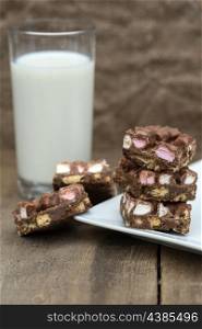 Rocky road squares on rustic background with glass of milk