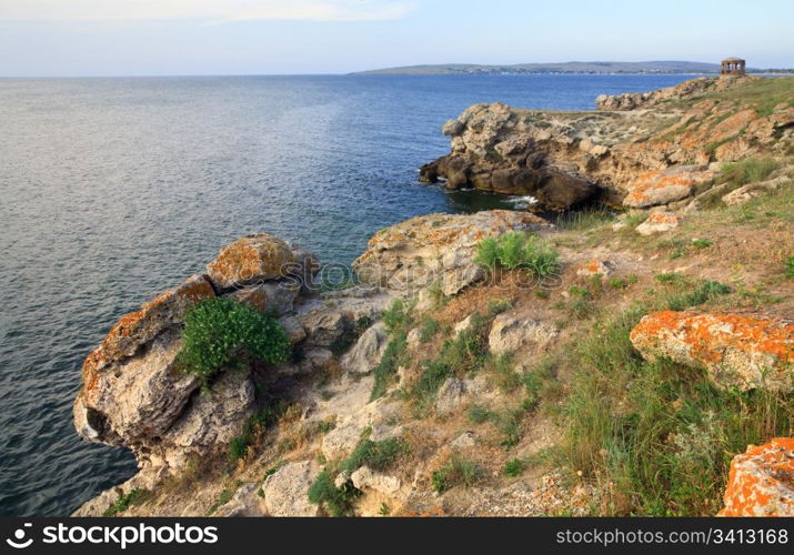 Rocky summer coastline and cape with pavilion