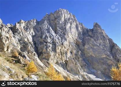 rocky wall of a peak mountain under blue sky