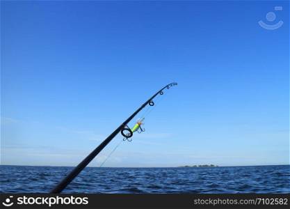 rod with fishing line stretched and crank bait fishing on the sea