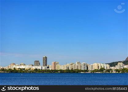 Rodrigo de Freitas lagoon in Rio de Janeiro, one of the main tourist attractions in the city surrounded by mountains and buildings on a sunny day with blue sky. Rodrigo de Freitas lagoon in Rio de Janeiro, one of the main tourist attractions in the city