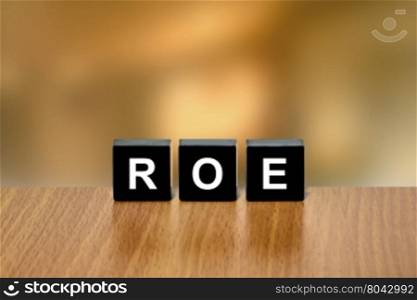 ROE or return on equity on black block with blurred background