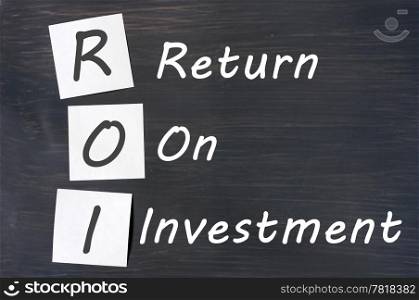 ROI acronym for Return on Investment written with chalk on a blackboard