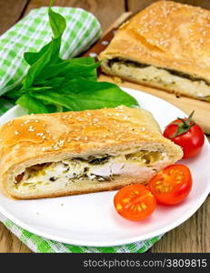 Roll layered with spinach and cheese, tomatoes in a dish on a napkin on the background of wooden boards