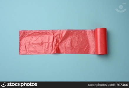 roll of red transparent plastic bags for trash can on blue background, top view