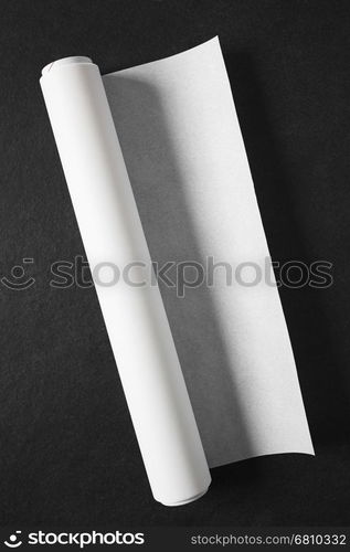 Roll of white baking paper photographed overhead on slate with natural light