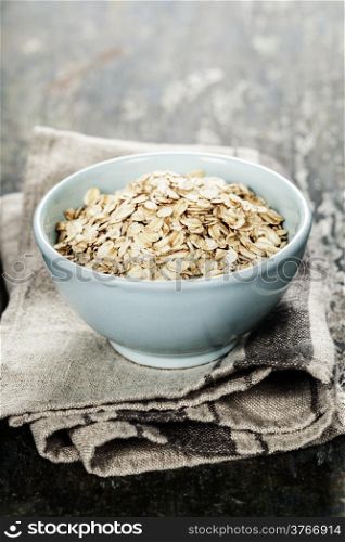 Rolled oats in a bowl on wooden board