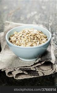 Rolled oats in a bowl on wooden board