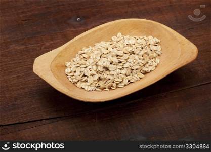 rolled oats on a rustic wooden bowl against old and cracked table
