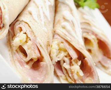 rolled pancakes stuffed ham and cheese. Shallow depth-of-field.