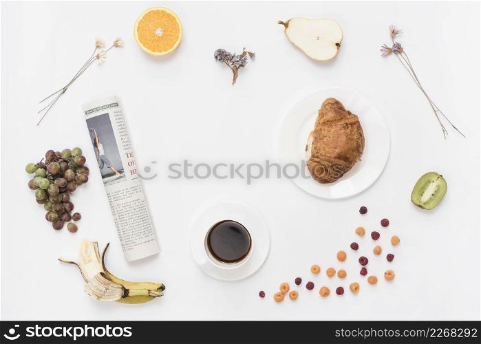 rolled up newspaper with coffee cup croissant fruits white background