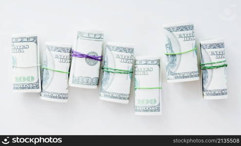 rolled up one hundred us dollar bills tied with rubber white background