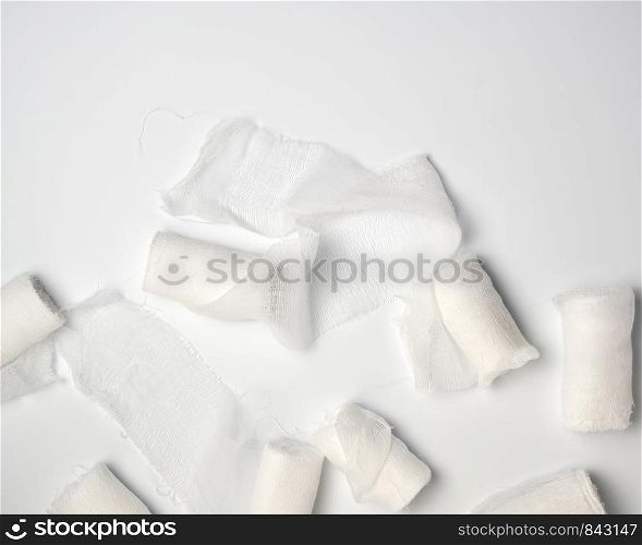 rolled up white sterile medical bandages on a white background, copy space