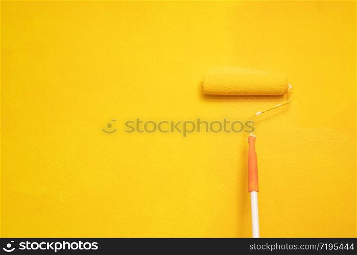 Roller Brush Painting, hand worker painting on surface wall Painting apartment, renovating with yellow color paint. Leave empty copy space to write descriptive text beside.