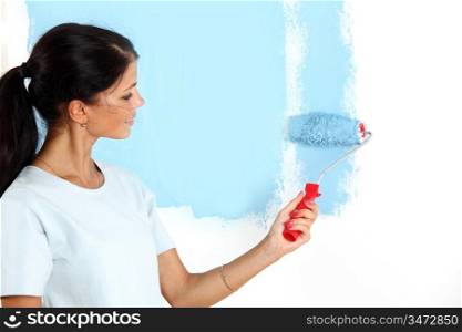 roller in woman hand paint on the wall