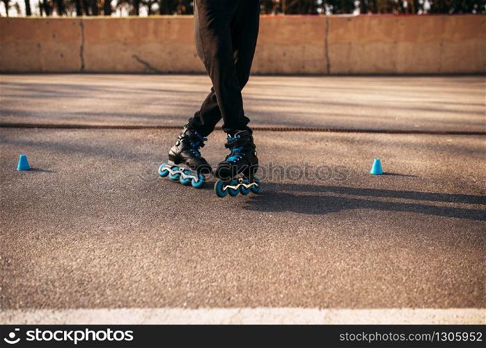 Roller skater legs in skates, balance exercise on sidewalk in city park. Male rollerskater leisure