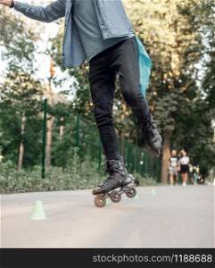 Roller skating, male teenager rolling on one leg in park. Urban roller-skating, active extreme sport outdoors