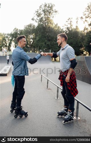 Roller skating, two male skaters rolling in summer park. Urban roller-skating, active extreme sport outdoors