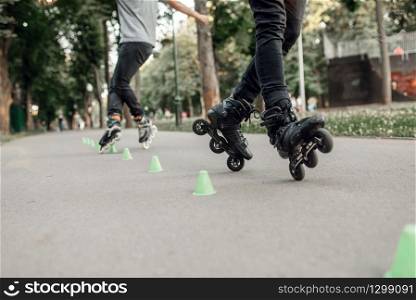 Roller skating, two skater rolling around the cones in park. Urban roller-skating, active extreme sport outdoors, youth leisure, rollerskating
