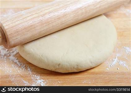 Rolling out a circle of pizza dough with a wooden rolling pin