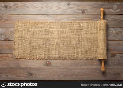 rolling pin and sacking burlap at wooden board rustic plank table background, top view