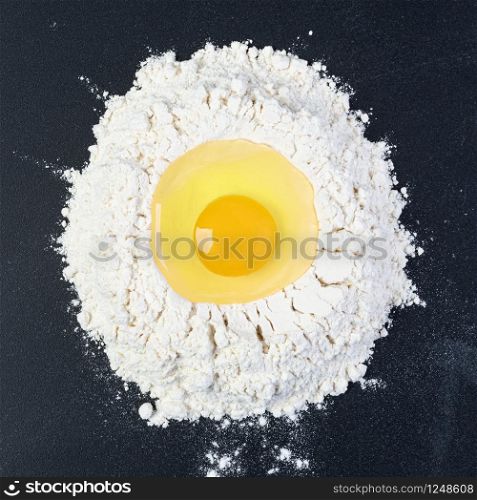 Rolling pin and white flour on a dark background. Top view.. Rolling pin and white flour on a dark background