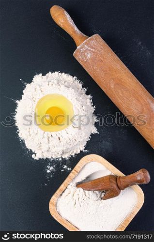 Rolling pin and white flour on a dark background. Top view.. Rolling pin and white flour on a dark background