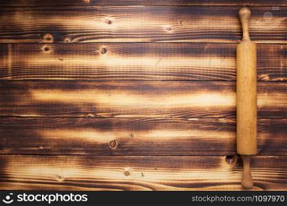 rolling pin at rustic board wooden plank background, top view