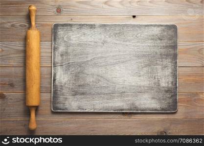 rolling pin at rustic wooden plank board table background, top view