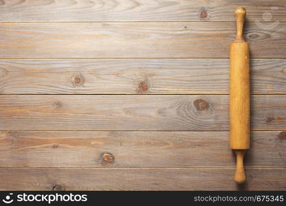 rolling pin at wooden board rustic plank table background, top view