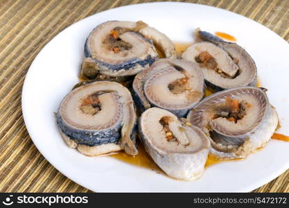 Rolls from a herring on a plate, on a straw support