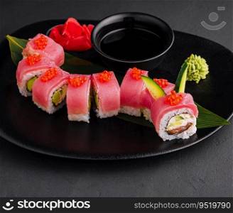 rolls with tuna and red caviar on a black plate