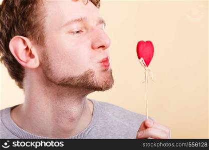 Romance gesture symbol feelings expression concept. Boy blowing kiss to heart. Young man holding love symbol making kissing face.. Boy blowing kiss to heart.