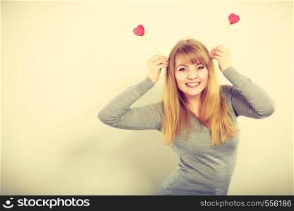 Romance leisure entertainment celebration feelings concept. Cheerful girl fooling with hearts. Young lady playing with love symbols on poles.. Cheerful girl fooling with hearts.