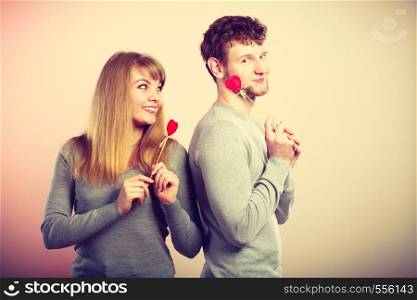 Romance love relationship valentines concept. Cheerful couple fooling together. Young man with woman holding hearts on sticks.. Cheerful couple fooling together.