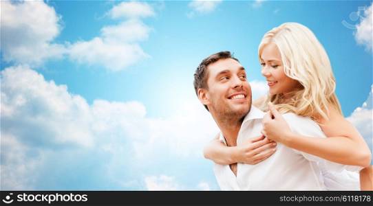 romance, people, love and dating concept - happy couple over blue sky and clouds background