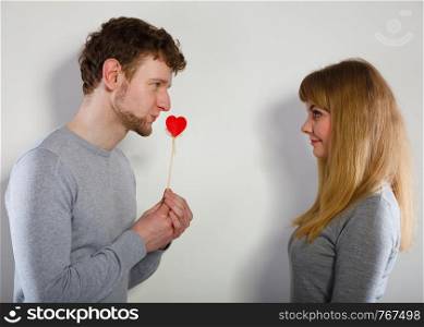Romance symbolism valentines concept. Man giving heart to his girl. Young male proffesing love to woman, by giving her heart.. Man giving heart to his girl.