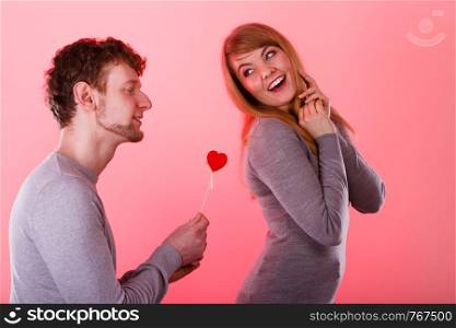 Romance symbolism valentines concept. Man giving heart to his girl. Young male proffesing love to woman, by giving her heart.. Man giving heart to his girl.