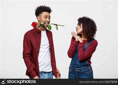 Romantic African American man in Love, holding a rose between his teeth standing in front of his girlfriend. Romantic African American man in Love, holding a rose between his teeth standing in front of his girlfriend.