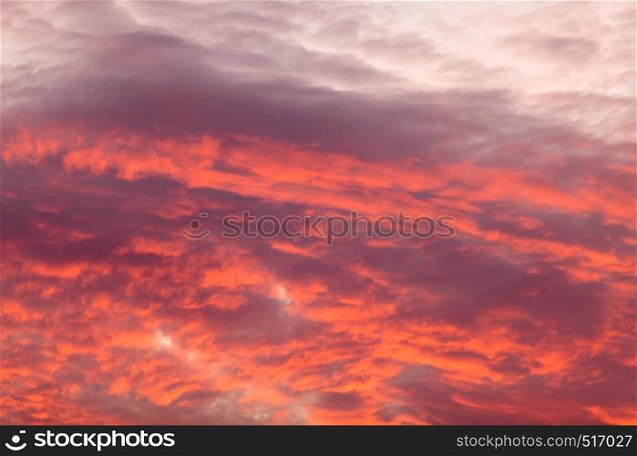 Romantic and dramatic cloud formation on dusk sky. Red and black warm landscape with sunlight.. Colorful warm clouds on sky at sunset